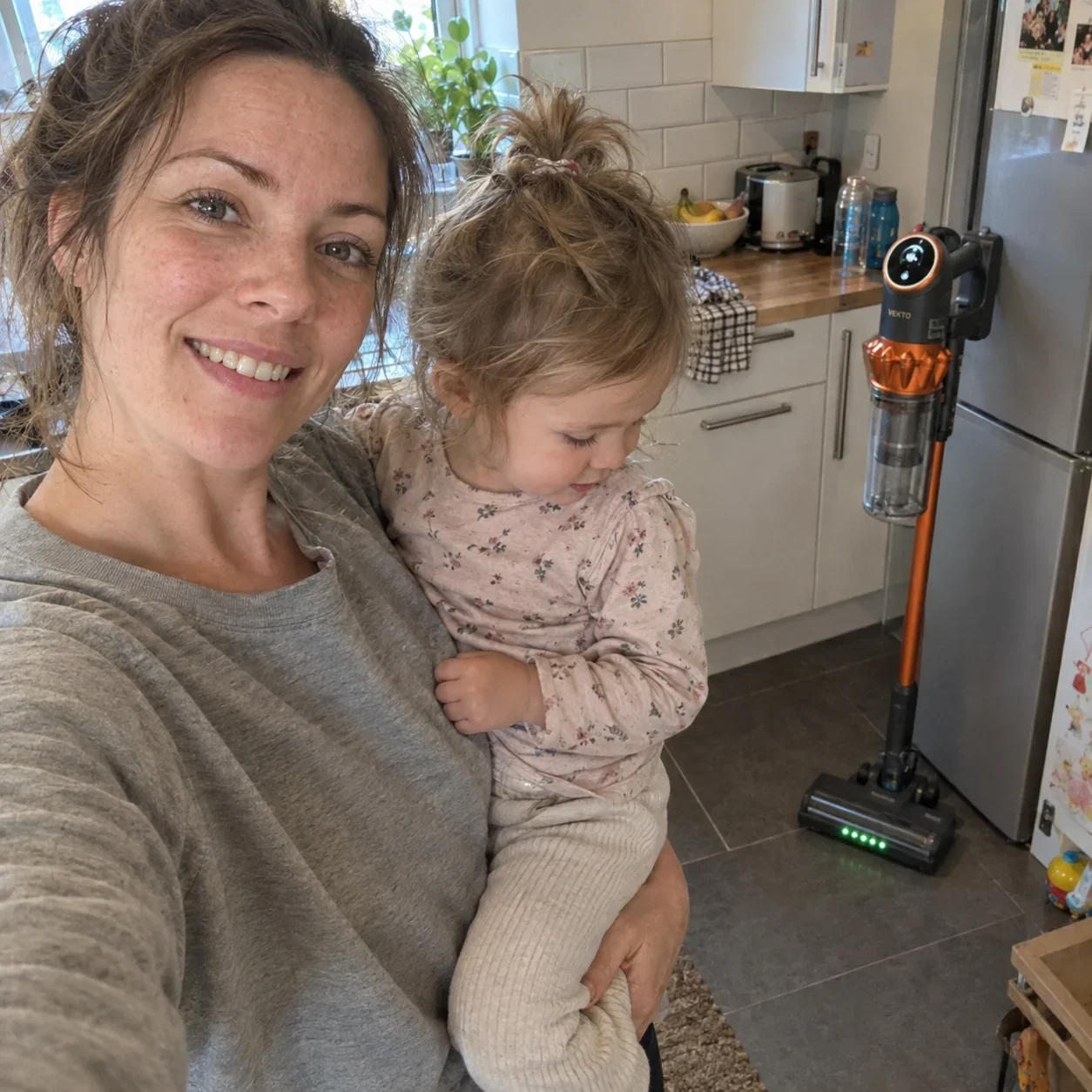 Hannah with her toddler in the kitchen, the Vekto Vacuum V18 standing behind them